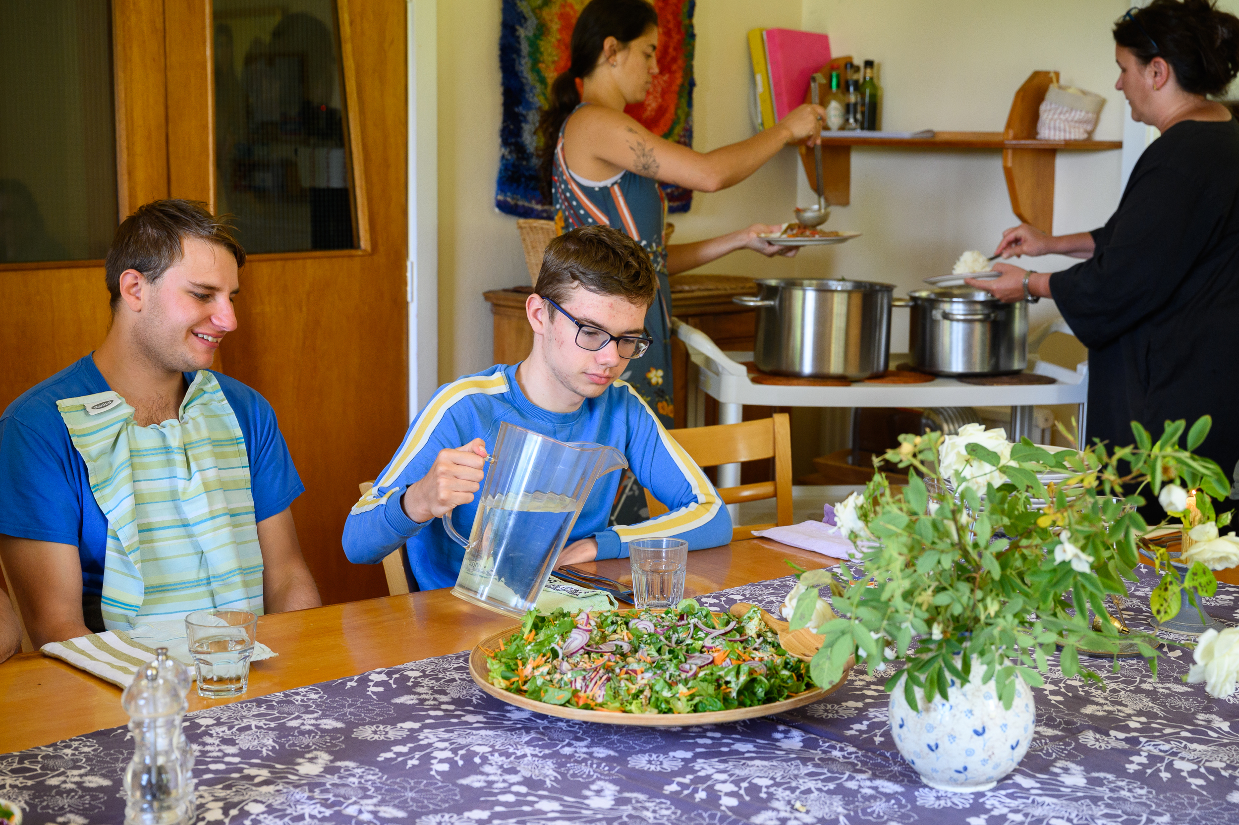 A young man pouring a glass of water at the dinner table