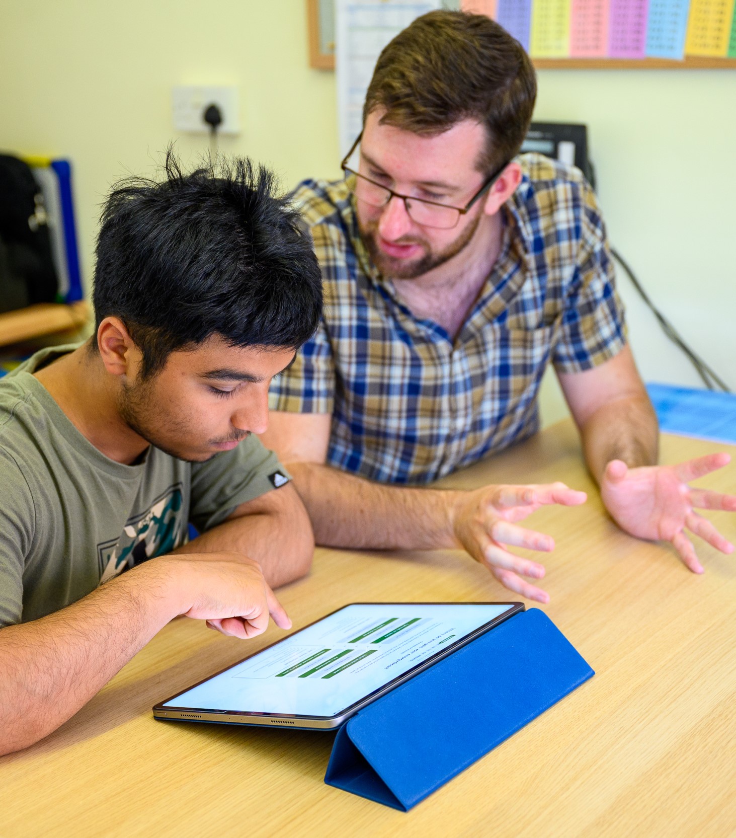 A student works on his iPad with a tutor