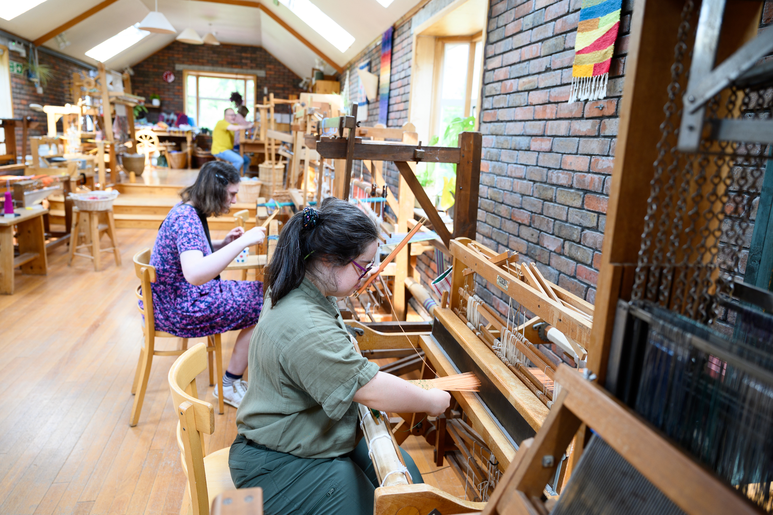 Two students working at the loom in our Weavery