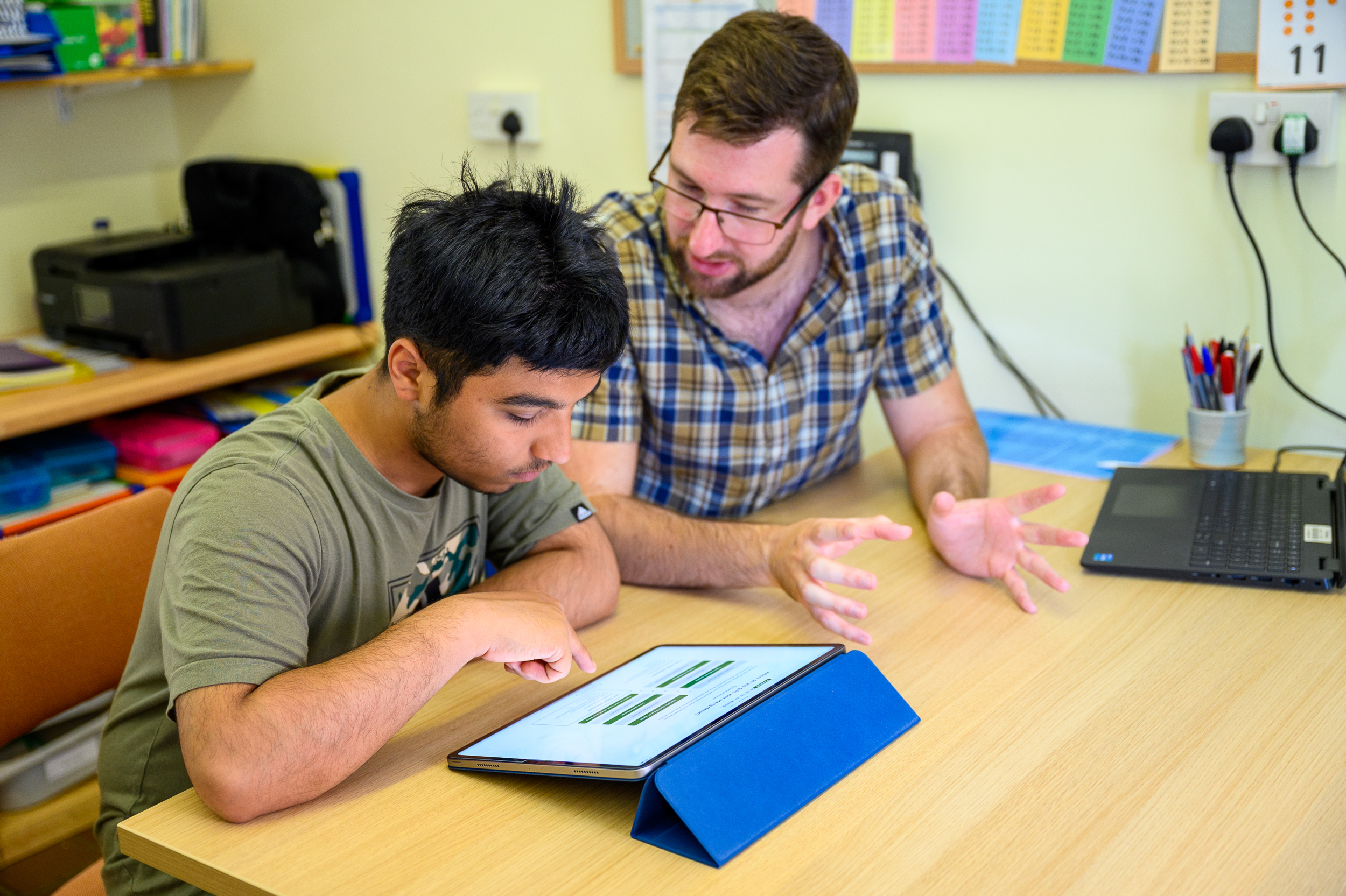 A student uses his iPad with help from his Tutor.