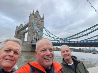Three men standing in front of a bridge in London