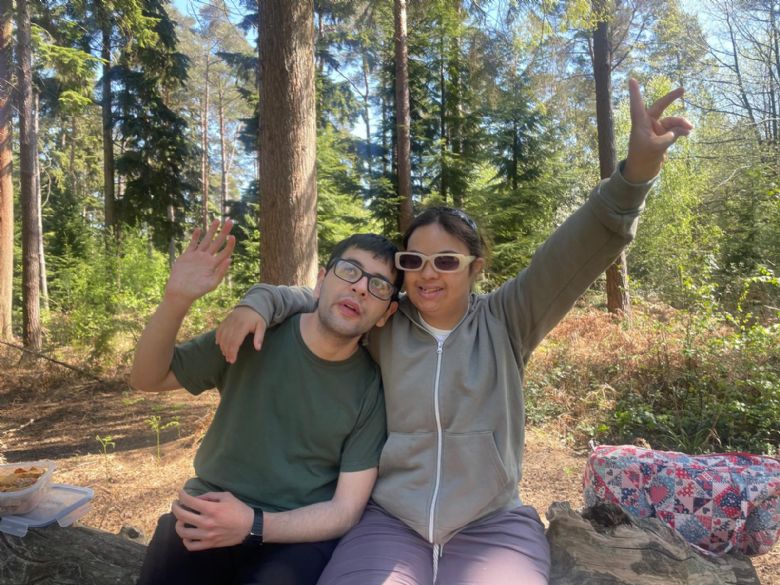 Two people sitting on a tree trunk in forest