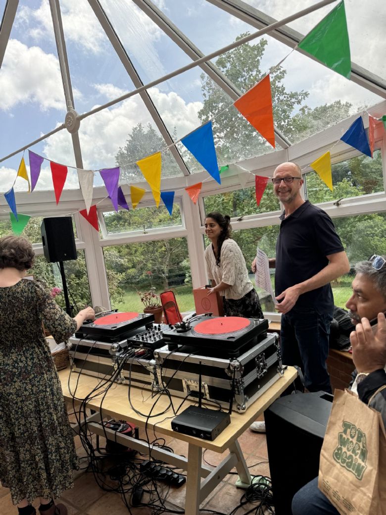 A few people standing next to a music mixing deck